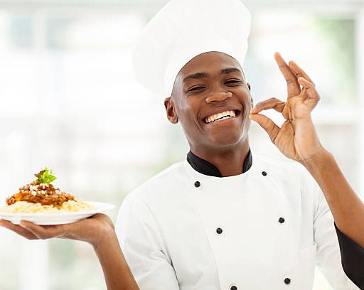 professional African chef holding spaghetti dish and making delicious hand sign